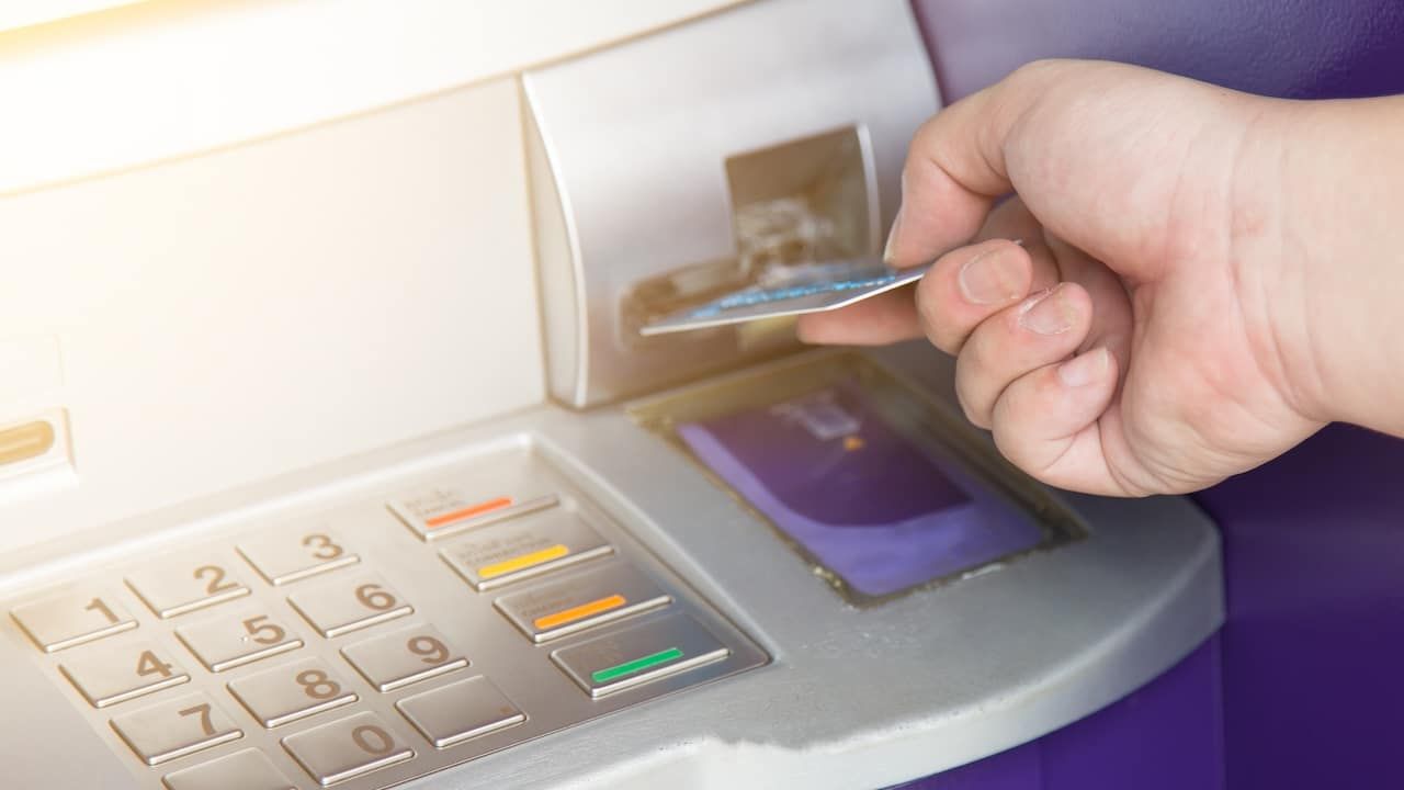 Hand inserting ATM credit card into bank machine