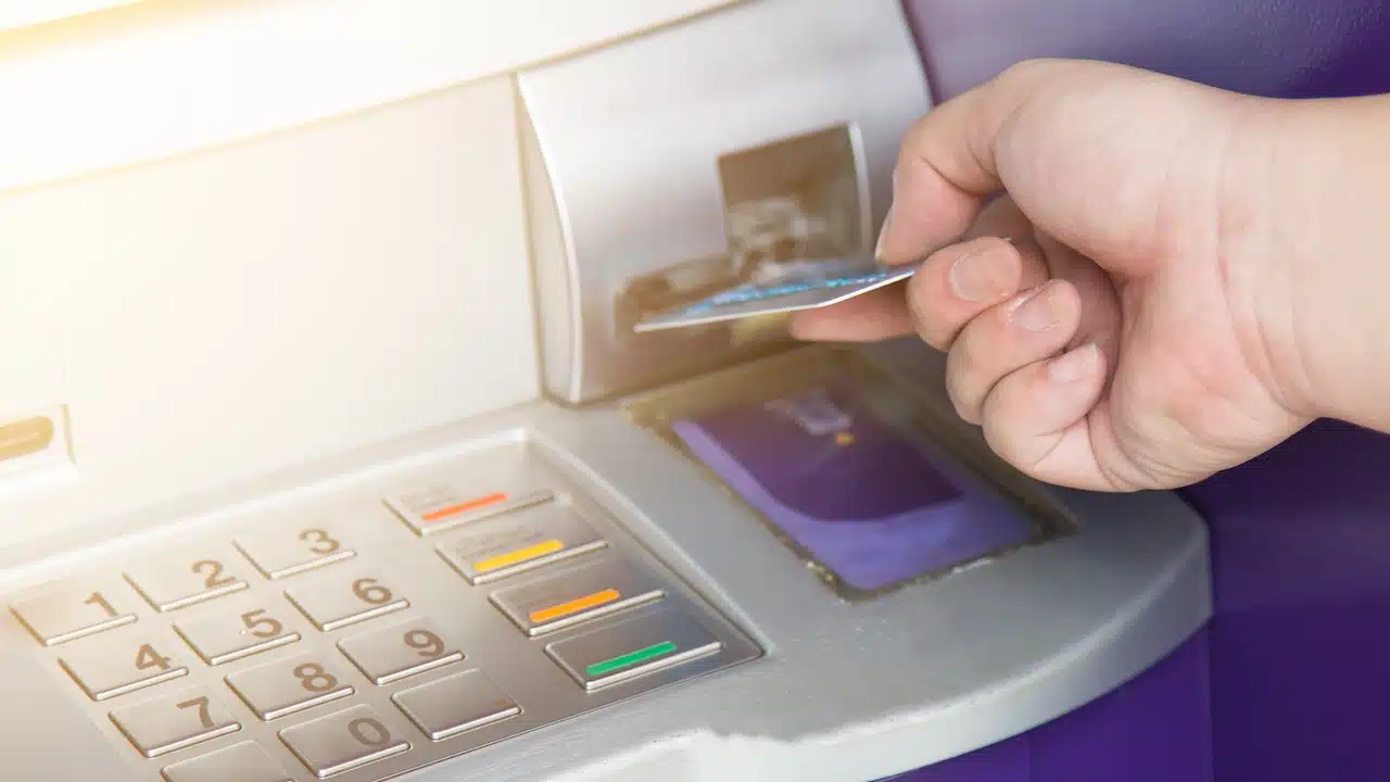 Hand inserting ATM credit card into bank machine