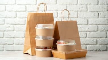Take out food in boxes and craft bag against brick background