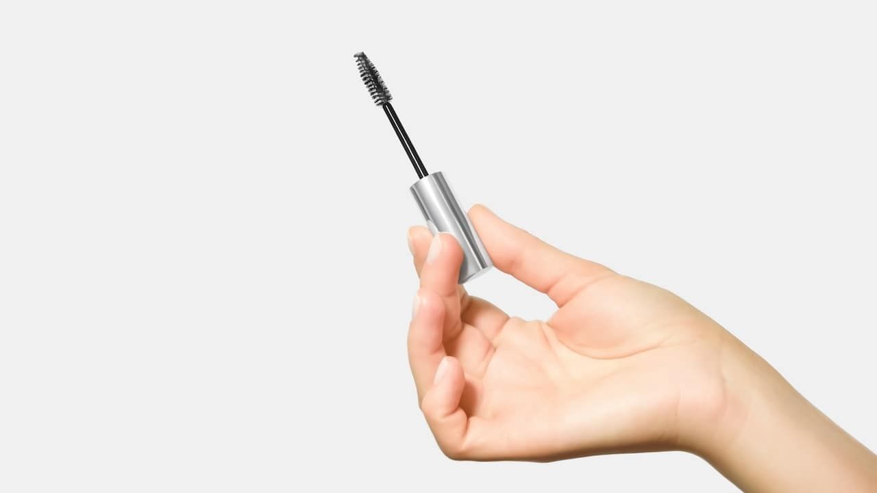 hand holding a brush with eyelash and eyebrow care serum