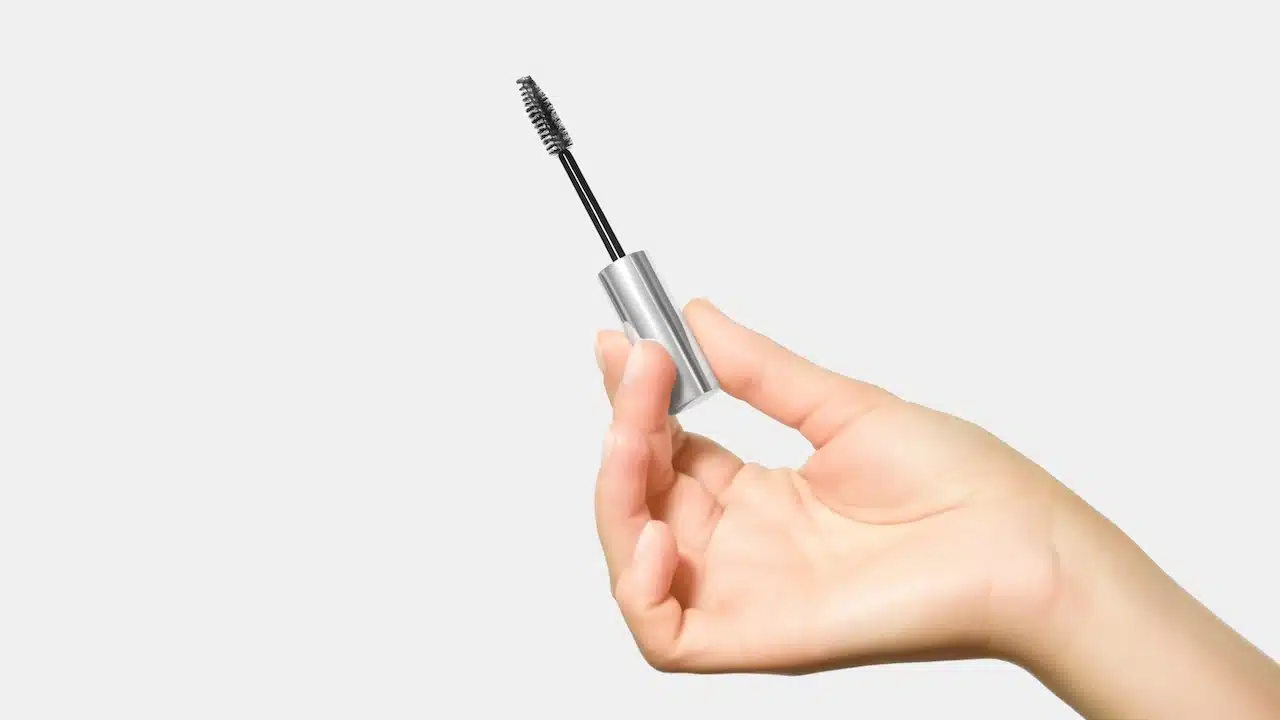 hand holding a brush with eyelash and eyebrow care serum