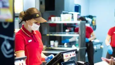 McDonald's employee at the cash register wearing a mask and gloves during a pandemic