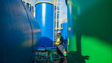 Male worker works permit industry visual inspection the row of big tanks for petrol station.