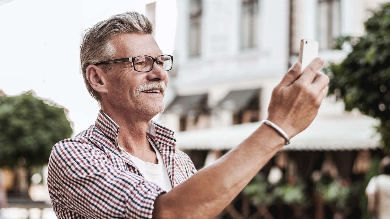 Smiling mature man in casual wear making selfie.