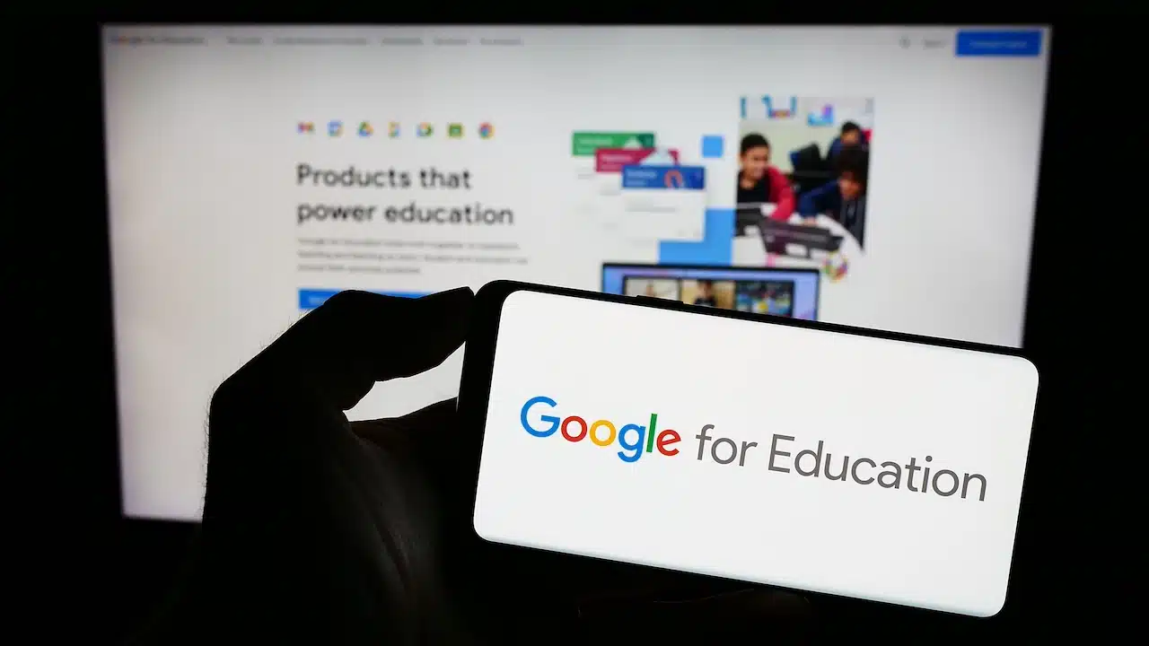 Person holding mobile phone with logo of software product Google for Education on screen in front of company web page