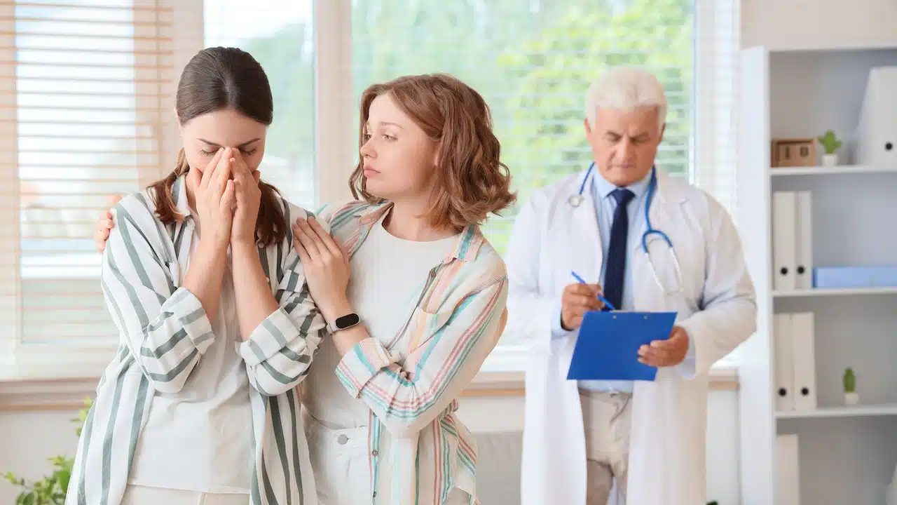 Upset young lesbian couple visiting fertility doctor about IVF in clinic