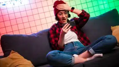 woman looking shocked, open mouth and eyes, cell phone playing online mobile game