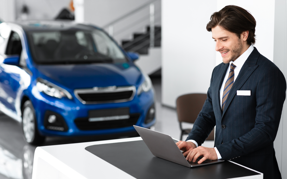 Dealer working at computer on sales floor.