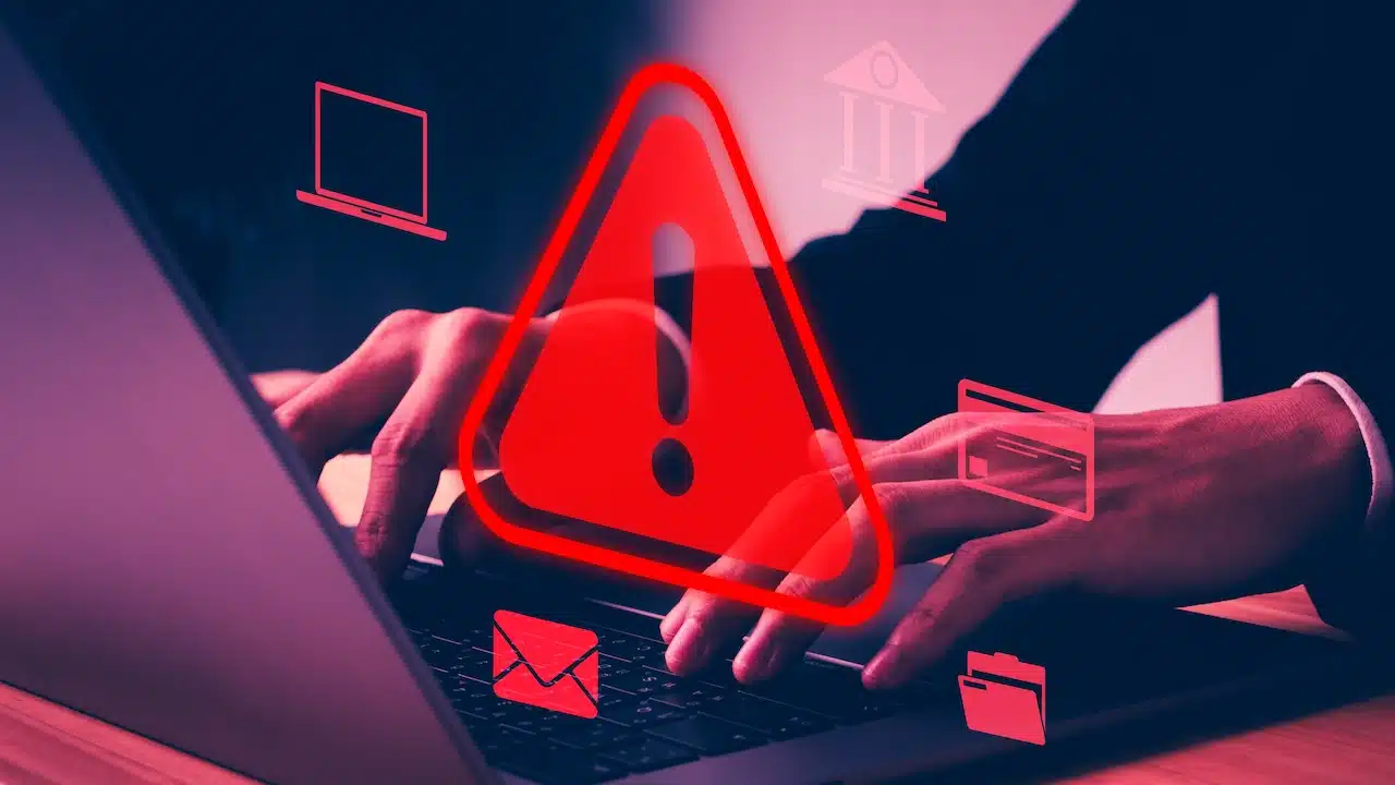 Cyber security alert concept showing hacker hands using laptop with red warning sign, system hack notification, data breach risk, digital attack, network protection, online privacy threat