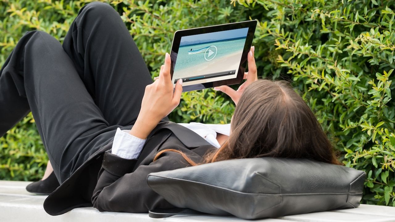 Young Businesswoman Lying On Bench Watching Video On Digital Tablet