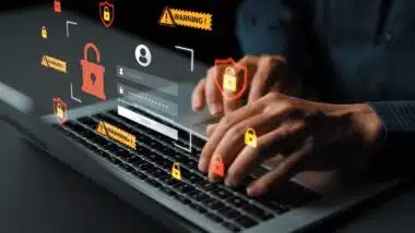 Hands Typing on Laptop with Security Icons and Warning Signs Signifying Cybersecurity Risks and Online Safety Measures