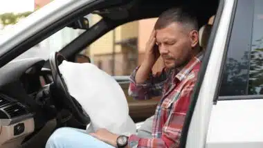 Injured man near opened airbag in automobile after car accident