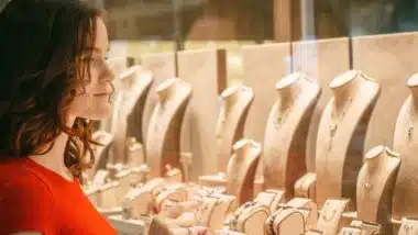 young woman is looking at jewelry in store window