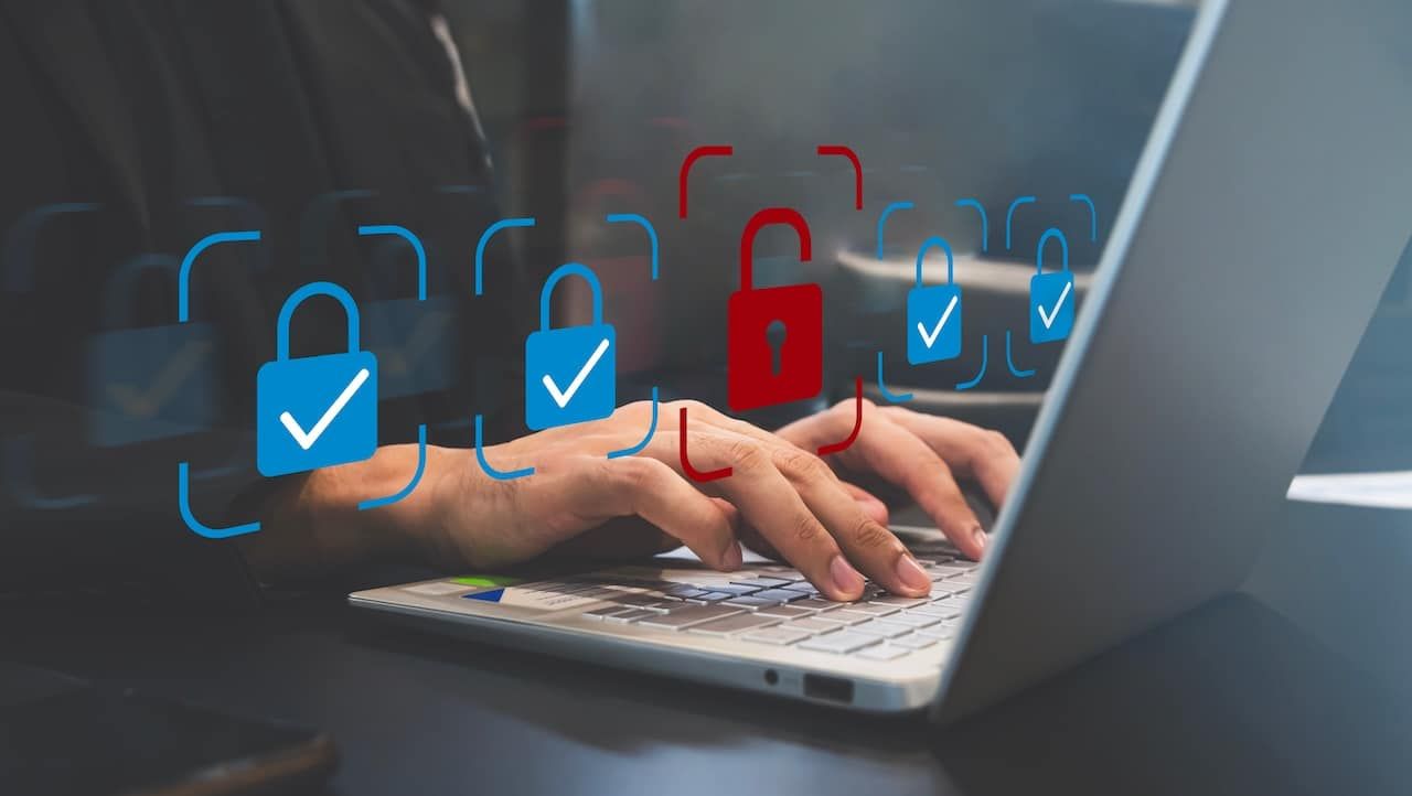 Cybersecurity Breach Concept: Man Working on Laptop with Red Unlocked Padlock Icon Representing Data Vulnerability.