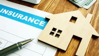 Home insurance form for homeowners and wood cut out model of home.