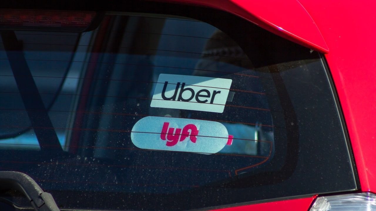 A view of a vehicle window with the decals for Uber and Lyft.