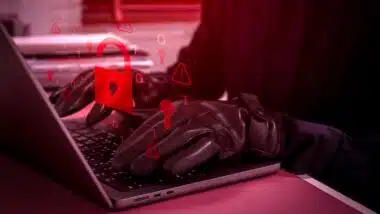 Cybersecurity threat concept showing hacker or scammer using laptop with glowing red unlocked padlock icon