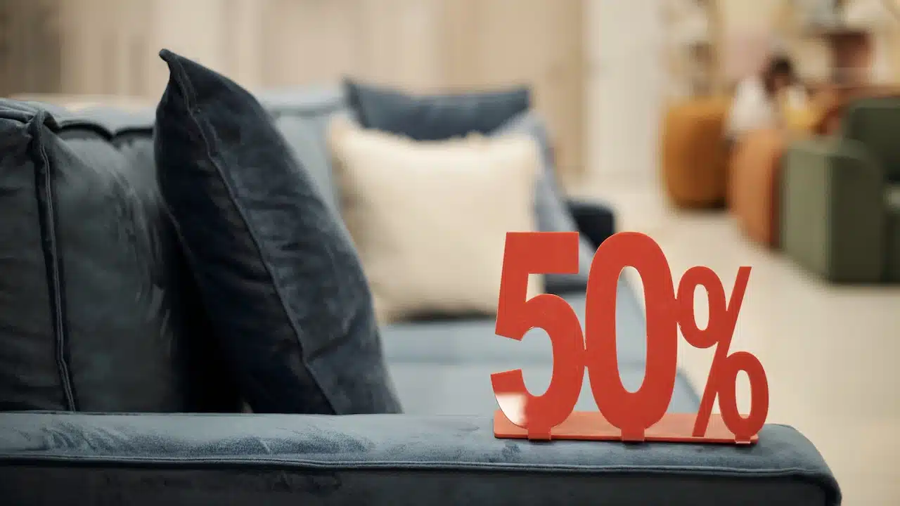 Closeup showing red fifty percent sign standing on blue sofa in furniture store