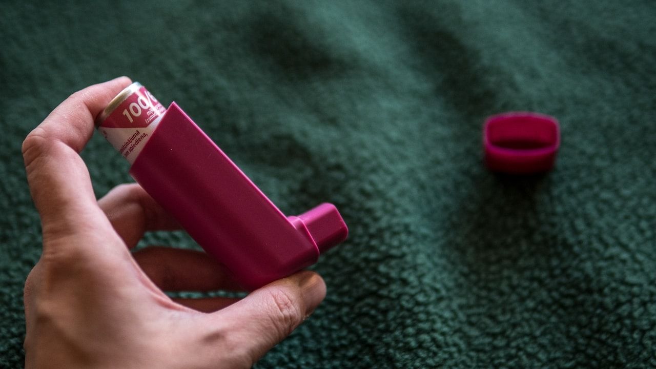 Hand Holding Asthma Inhaler on Dark Background