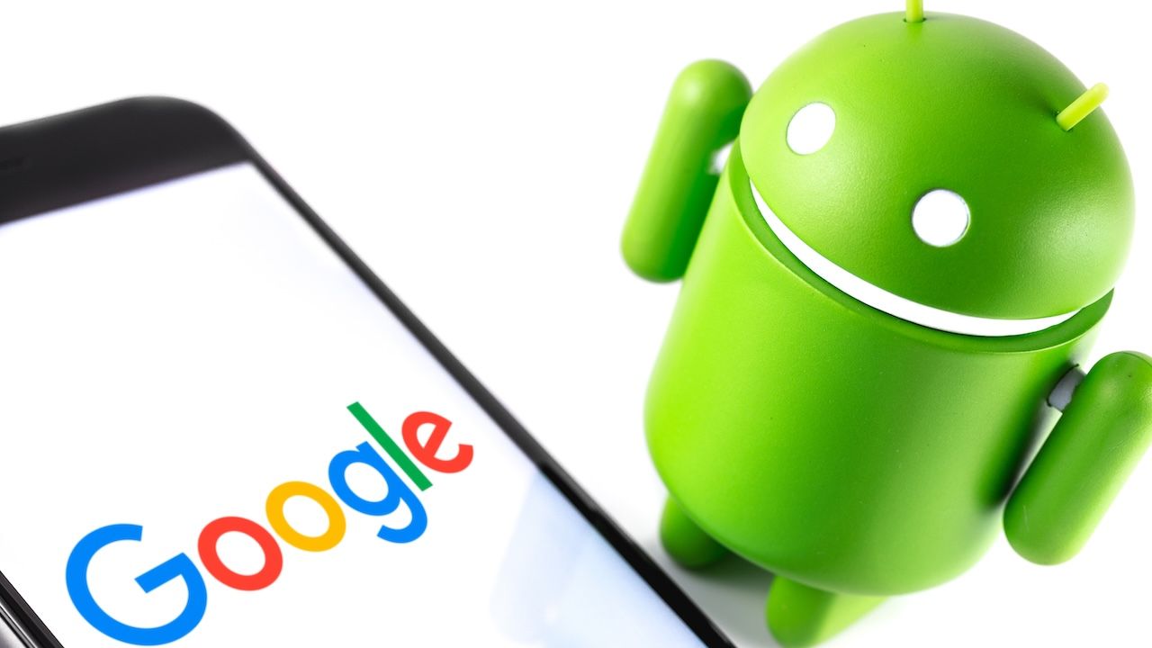 Google Android figure and smartphone with Google logo.