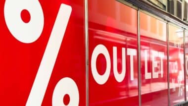 Vibrant outlet store window showcases bold white lettering and percentage signs, enticing customers with attractive sales and discounts