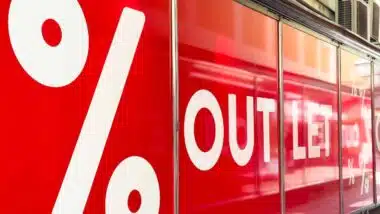 Vibrant outlet store window showcases bold white lettering and percentage signs, enticing customers with attractive sales and discounts
