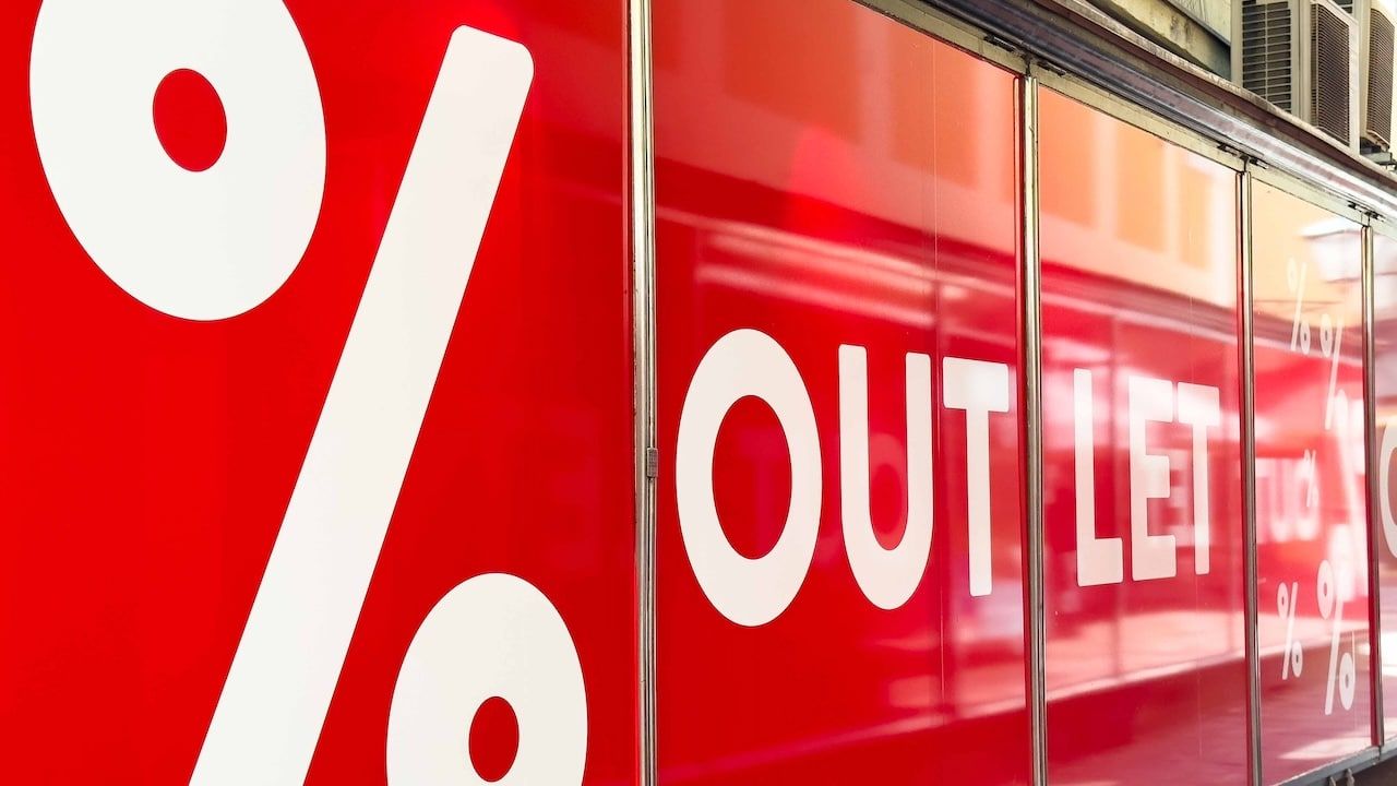 Vibrant outlet store window showcases bold white lettering and percentage signs, enticing customers with attractive sales and discounts
