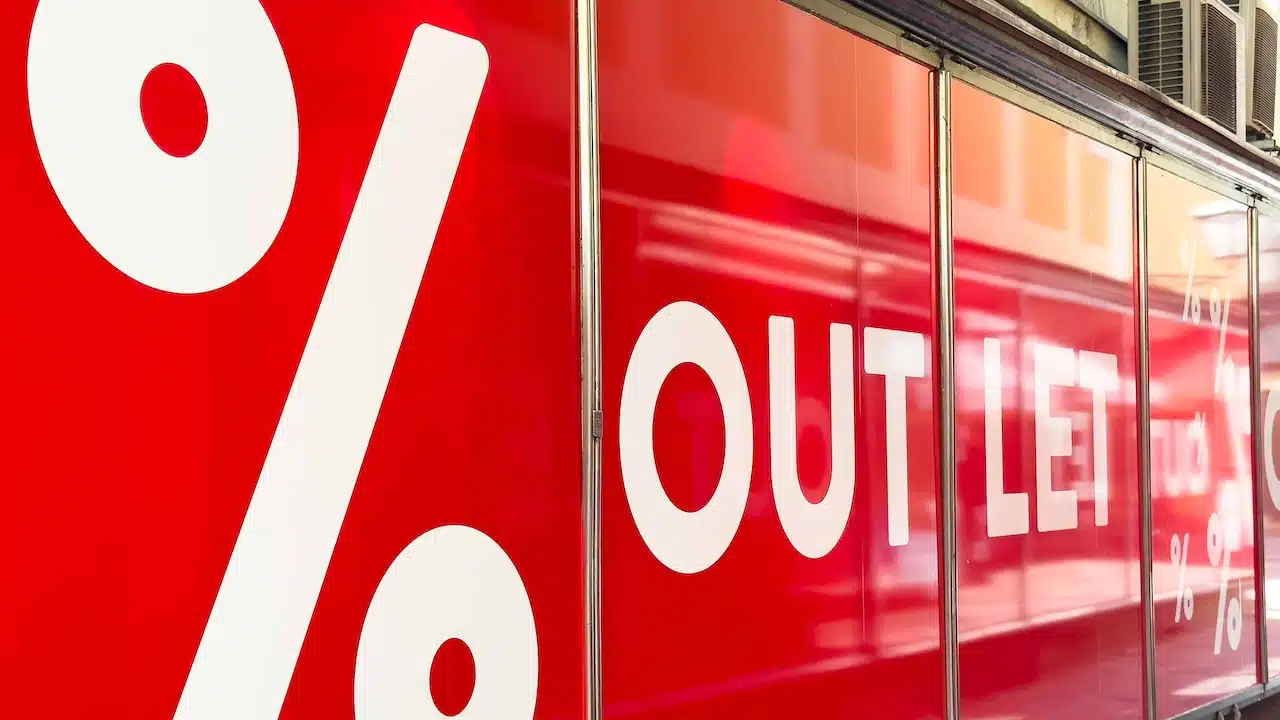 Vibrant outlet store window showcases bold white lettering and percentage signs, enticing customers with attractive sales and discounts