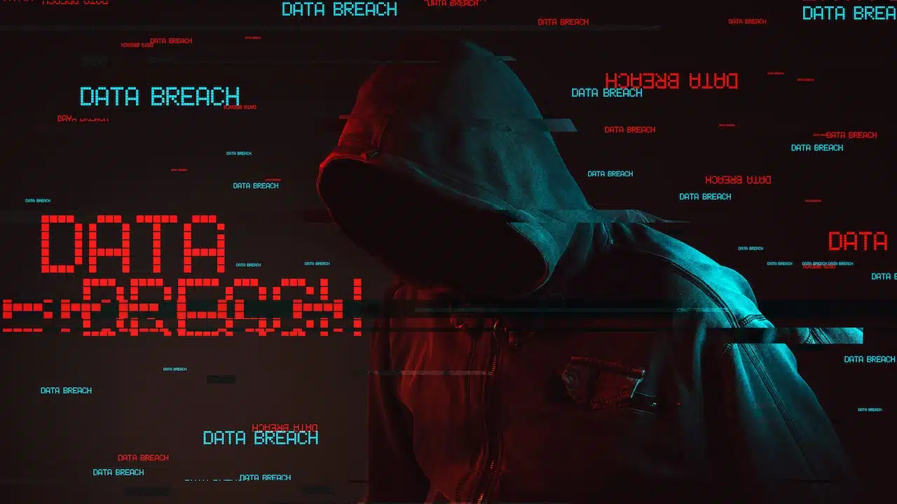 Data breach concept with faceless hooded male person, low key red and blue lit image and digital glitch effect