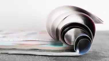Three open magazines on grey stone table