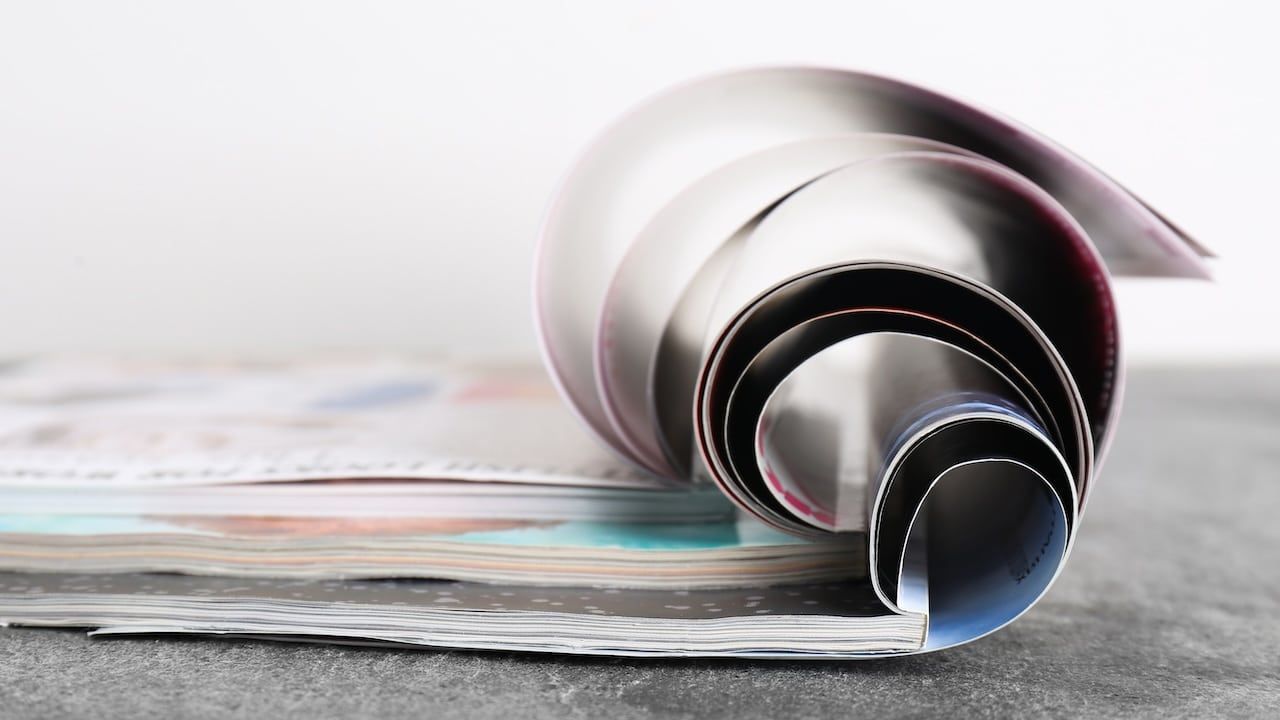 Three open magazines on grey stone table