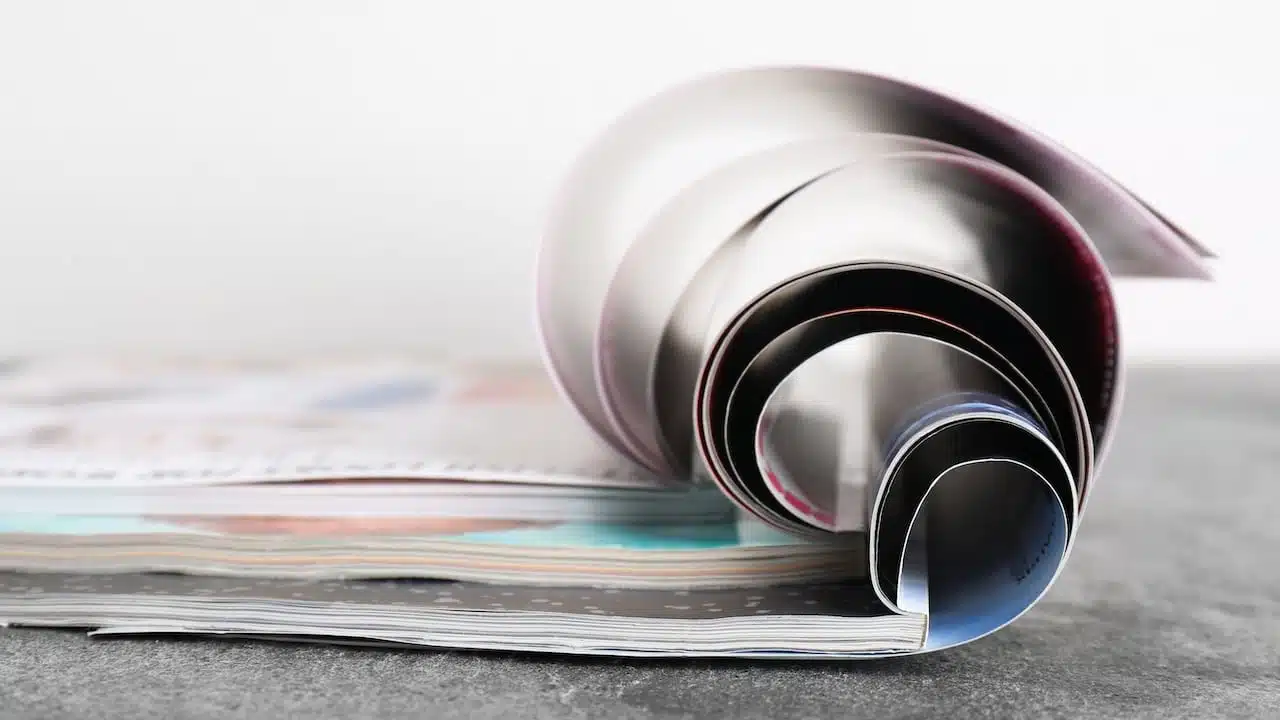 Three open magazines on grey stone table