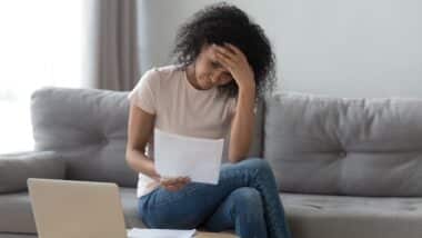 Stressed african woman holding papers calculate insurance bills