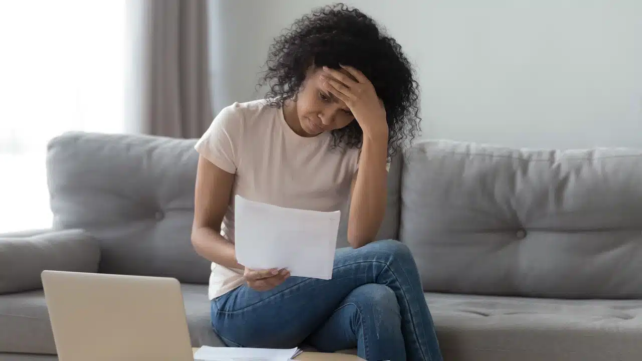 Stressed african woman holding papers calculate insurance bills