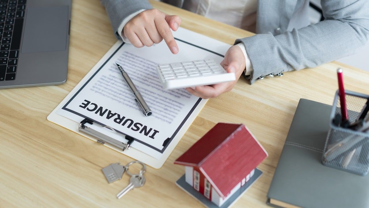 Insurance concept the estate broker pressing a calculator to calculate the price of the property.