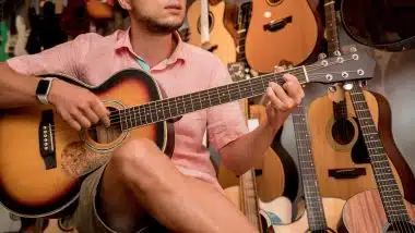 Young musician testing classical guitar in a guitar shop