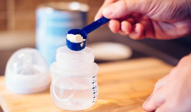 Father making baby formula in milk bottle for a newborn baby feed.