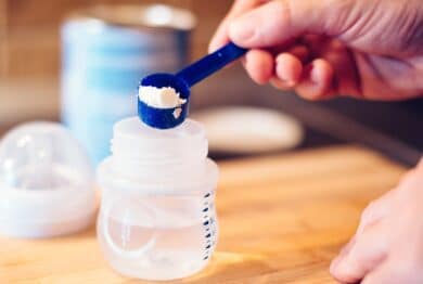 Father making baby formula in milk bottle for a newborn baby feed.