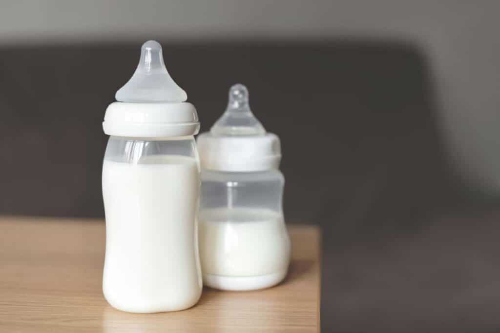 Baby bottles filled with milk sitting on a table, representing the baby bottle class actions.