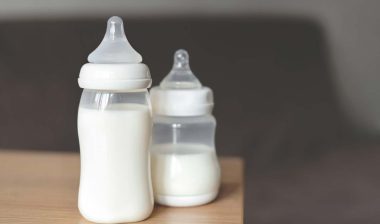 Baby bottles filled with milk sitting on a table, representing the baby bottle class actions.