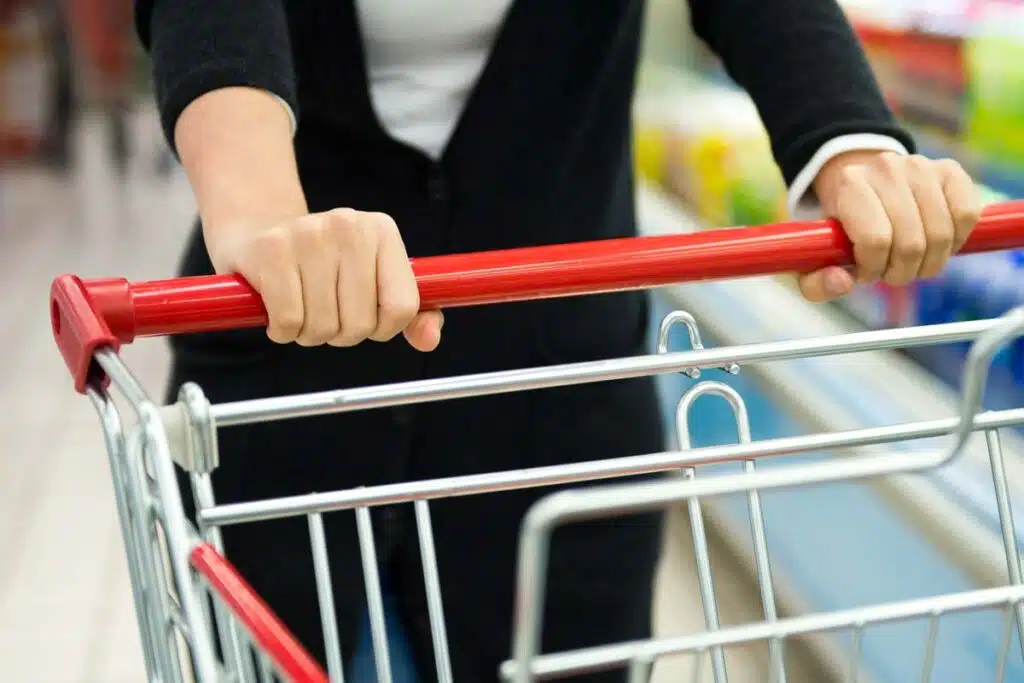 Close up of a womans hands pushing a shopping cart, representing top recalls for the week of June 24.