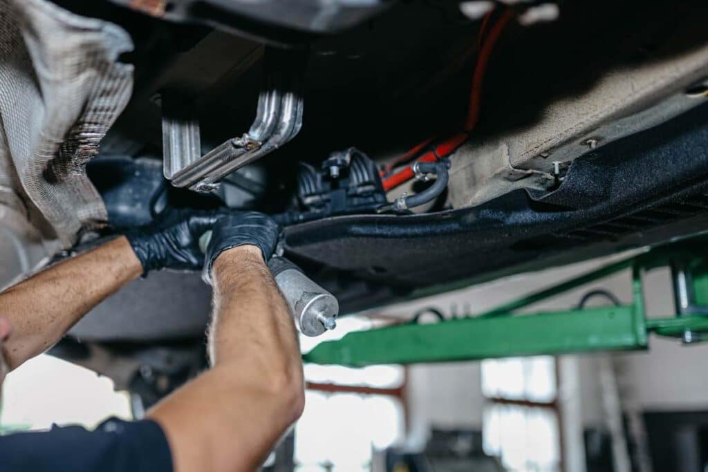A mechanic replacing a fuel pump on a diesel car, representing GM fuel pump class action settlement.
