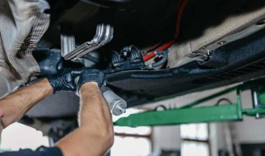 A mechanic replacing a fuel pump on a diesel car, representing GM fuel pump class action settlement.