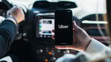 A woman using the Uber app while riding in the backseat of a car, representing Uber sexual assault MDL.