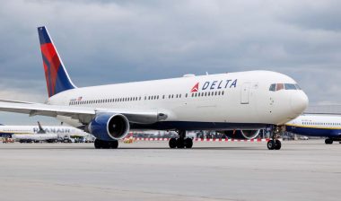 A Delta airlines plane on a tarmac at an airport, representing DOJ probe into Delta flight cancellations.