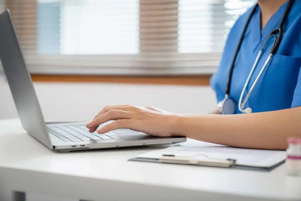 Close up of a nurse typing on a laptop, representing the PruittHealth class action.