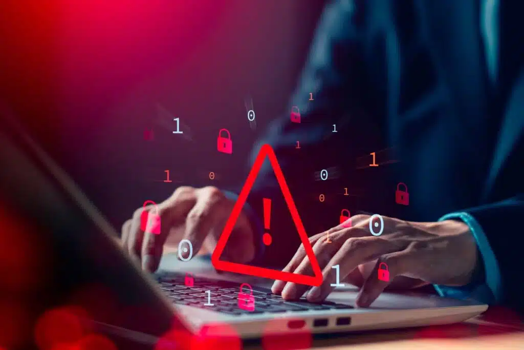 Close up of a man typing on a laptop with a data warning concept symbol overlay, representing the Evolve Bank data breach.