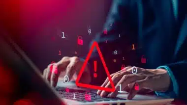 Close up of a man typing on a laptop with a data warning concept symbol overlay, representing the Evolve Bank data breach.