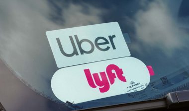 Close up of Uber and Lyft sticker in a car window, representing the Uber and Lyft settlement.