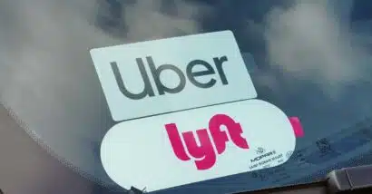 Close up of Uber and Lyft sticker in a car window, representing the Uber and Lyft settlement.